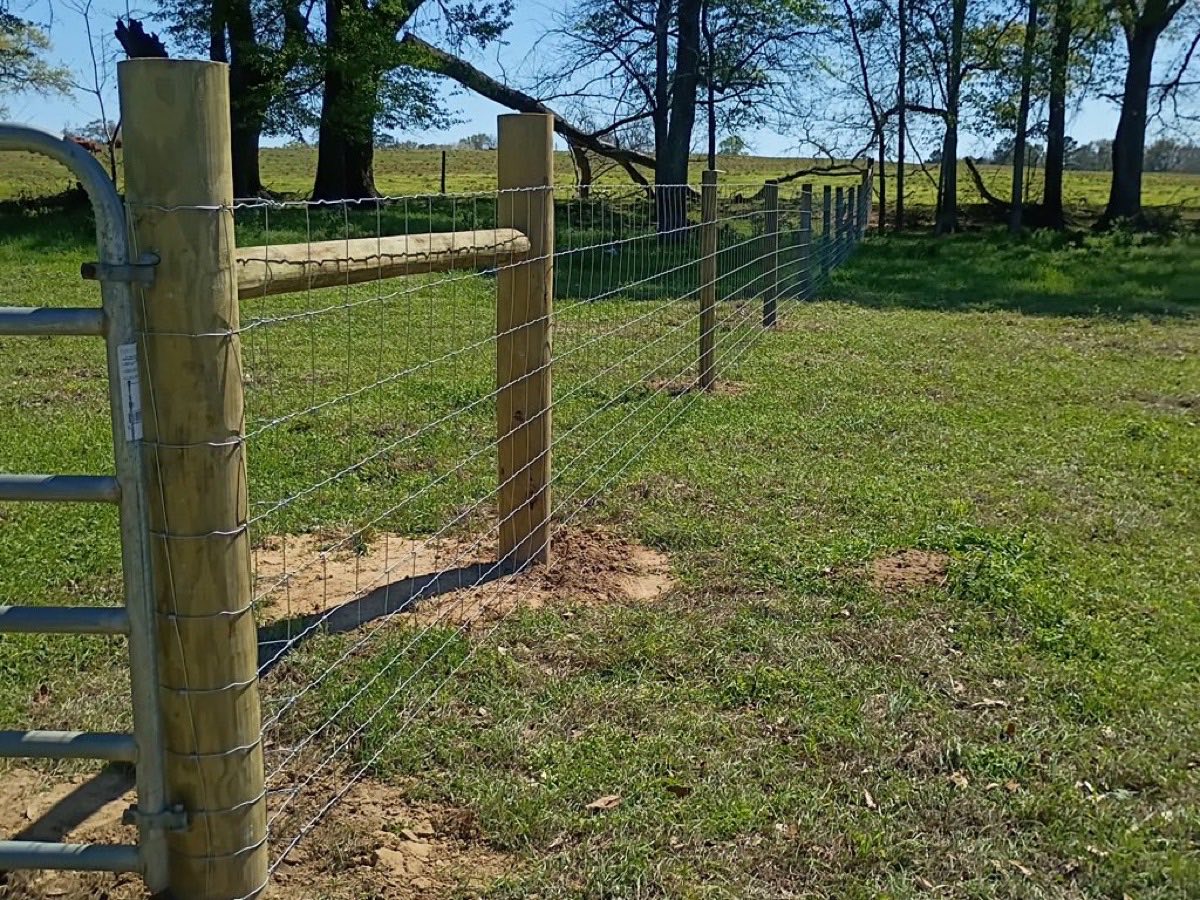 Wire field fence with a metal gate securing a rural property